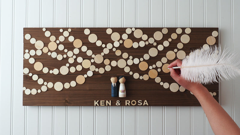 Personalized Wedding Guest book with hand-painted bride and groom peg dolls.   Have your guests sign a wooden circle, depicting lantern lights.  Hang this guestbook after the wedding to preserve beautiful memories of your special day for many years to come.  This 28"x11" wooden Wedding guest book alternative consist of up to 110 sign-able wooden circles.  It is sufficient for at least 150 guests.